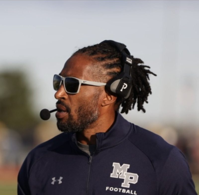 Coach Dante Coles wearing a headset and sunglasses on the sideline