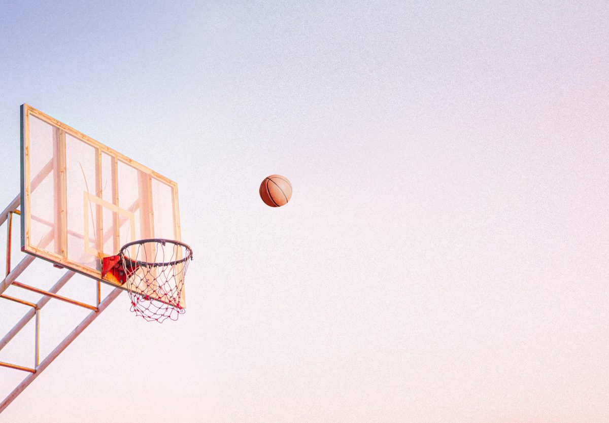Basketball hoop against the sky with a ball in mid-air